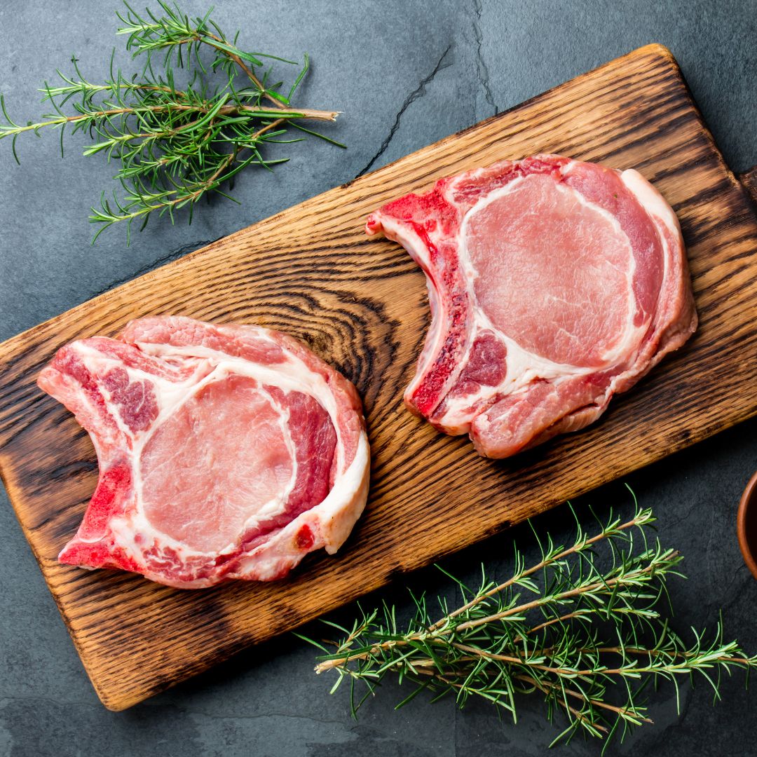 Heritage pork chops on a wooden cutting board from Forester Family Farm in Shell Knob, Missouri.